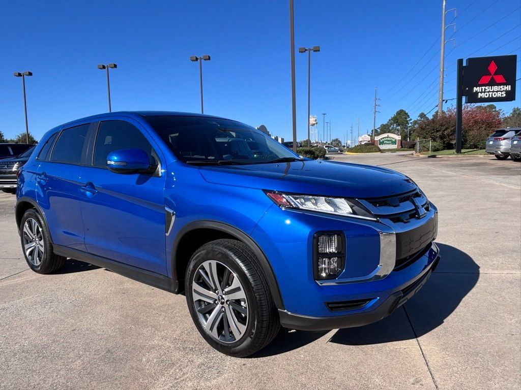 Blue Mitsubishi SUV parked in a dealership lot under a clear sky