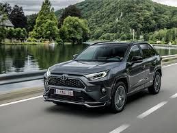 Black SUV driving on a lakeside road with green hills in the background