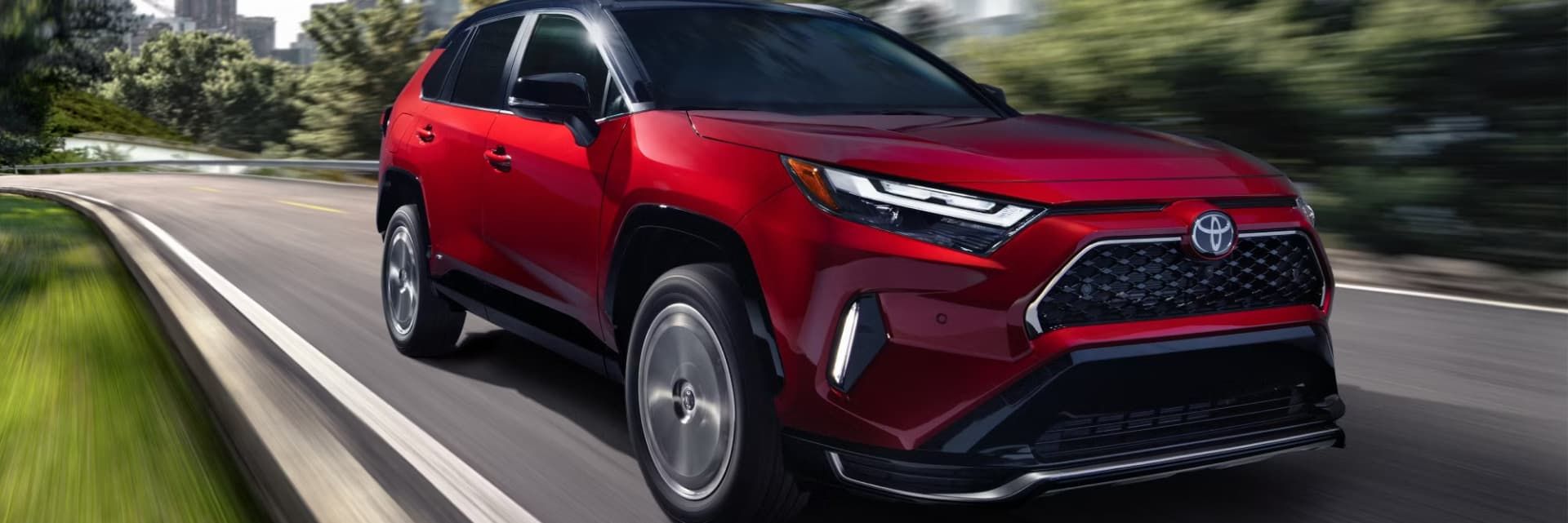 Red SUV driving on a winding road through a green wooded area