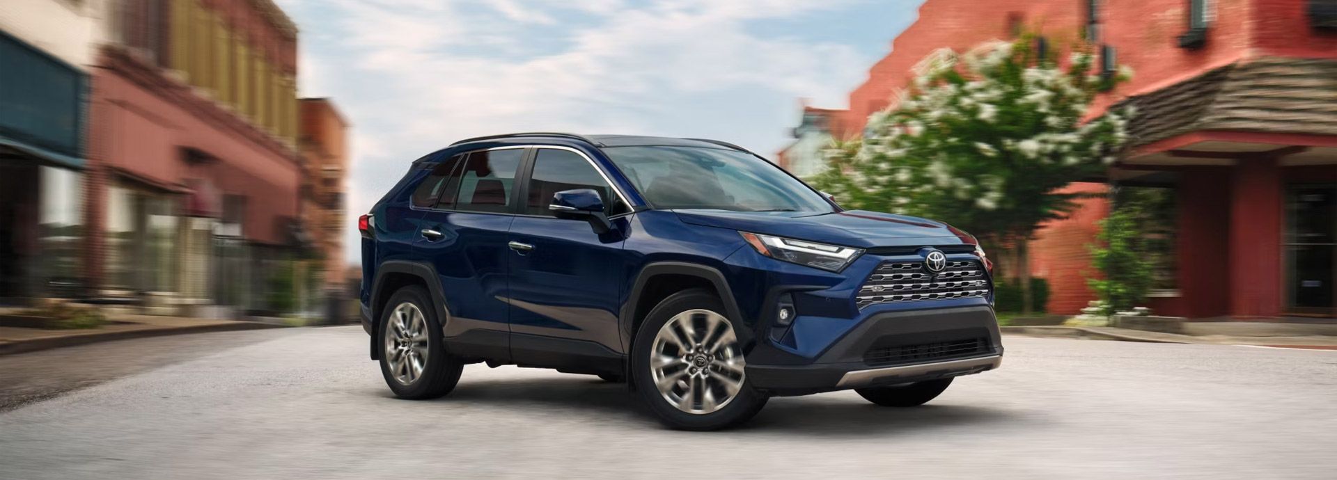 Blue SUV parked on a city street between brick buildings, front three-quarter view