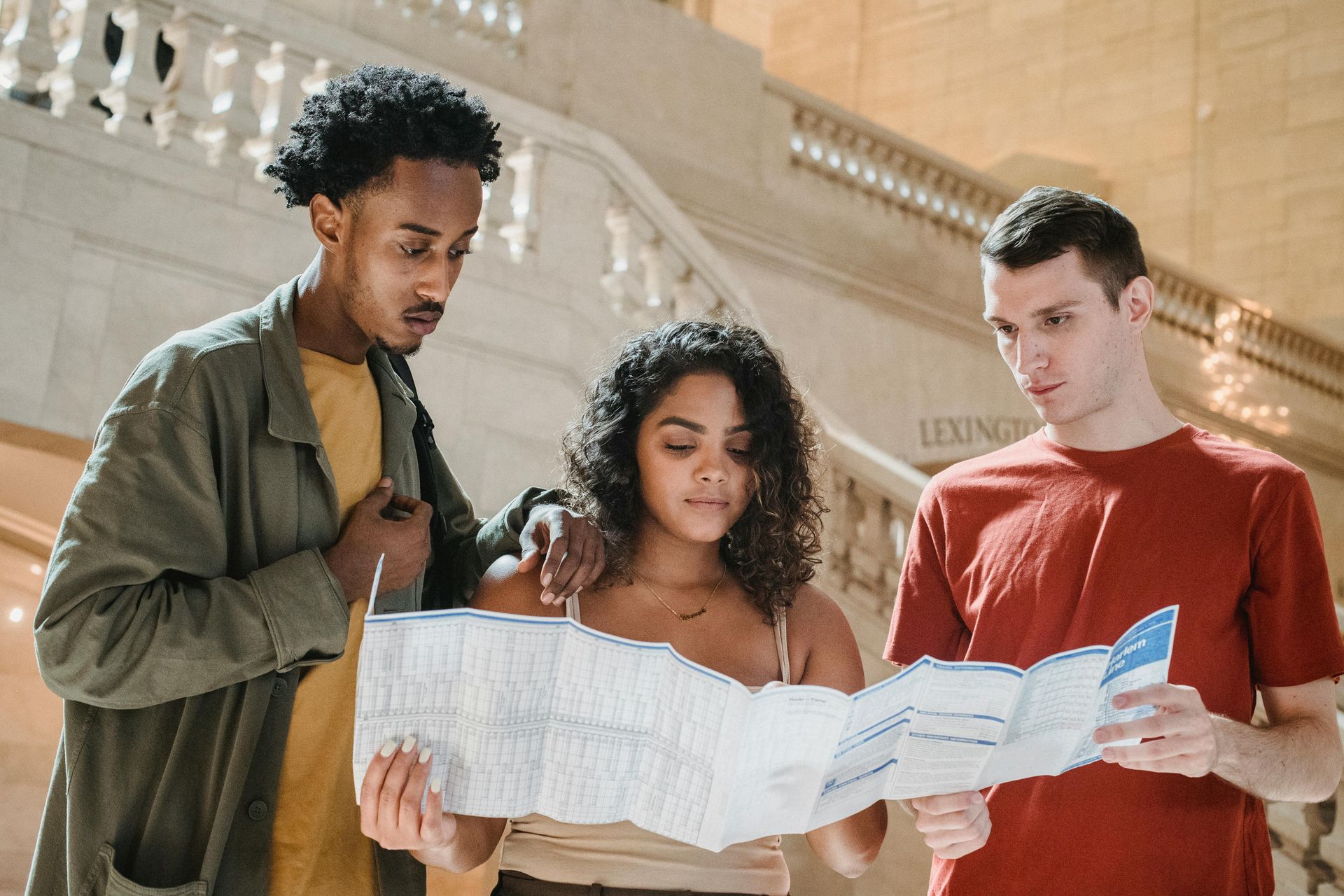 Three people studying a folded map together on a staircase outdoors, focused and talking.