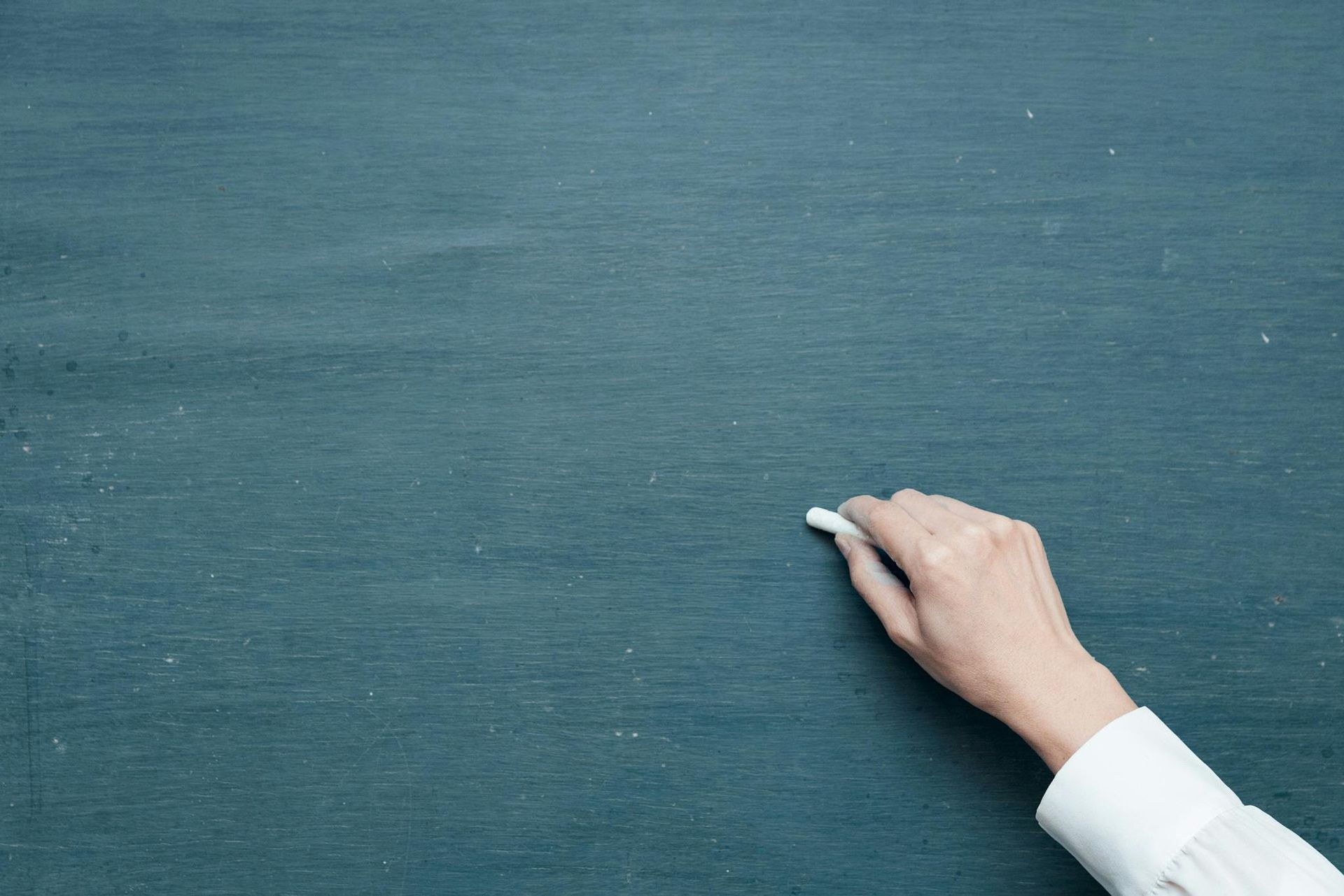 Hand writing on a green chalkboard with white chalk