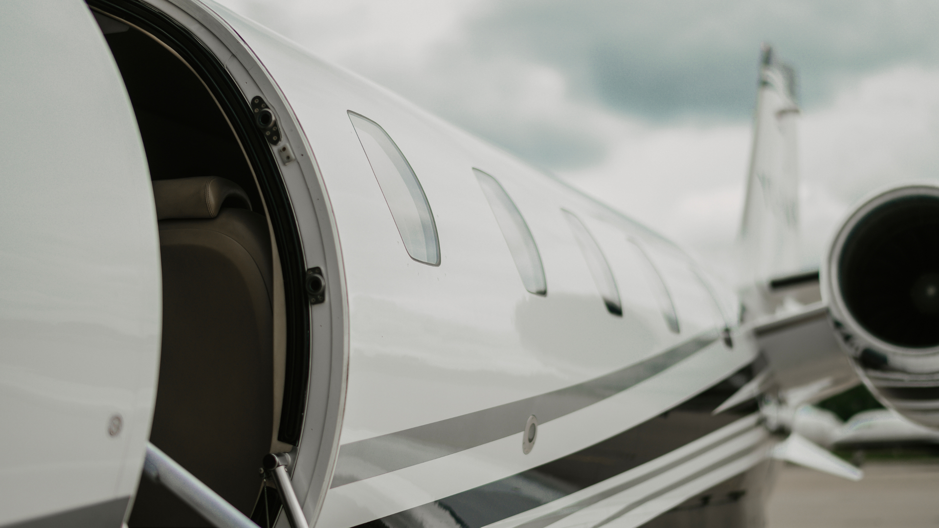 Close-up of a white private jet on the tarmac, showing the fuselage and engine nozzle at right