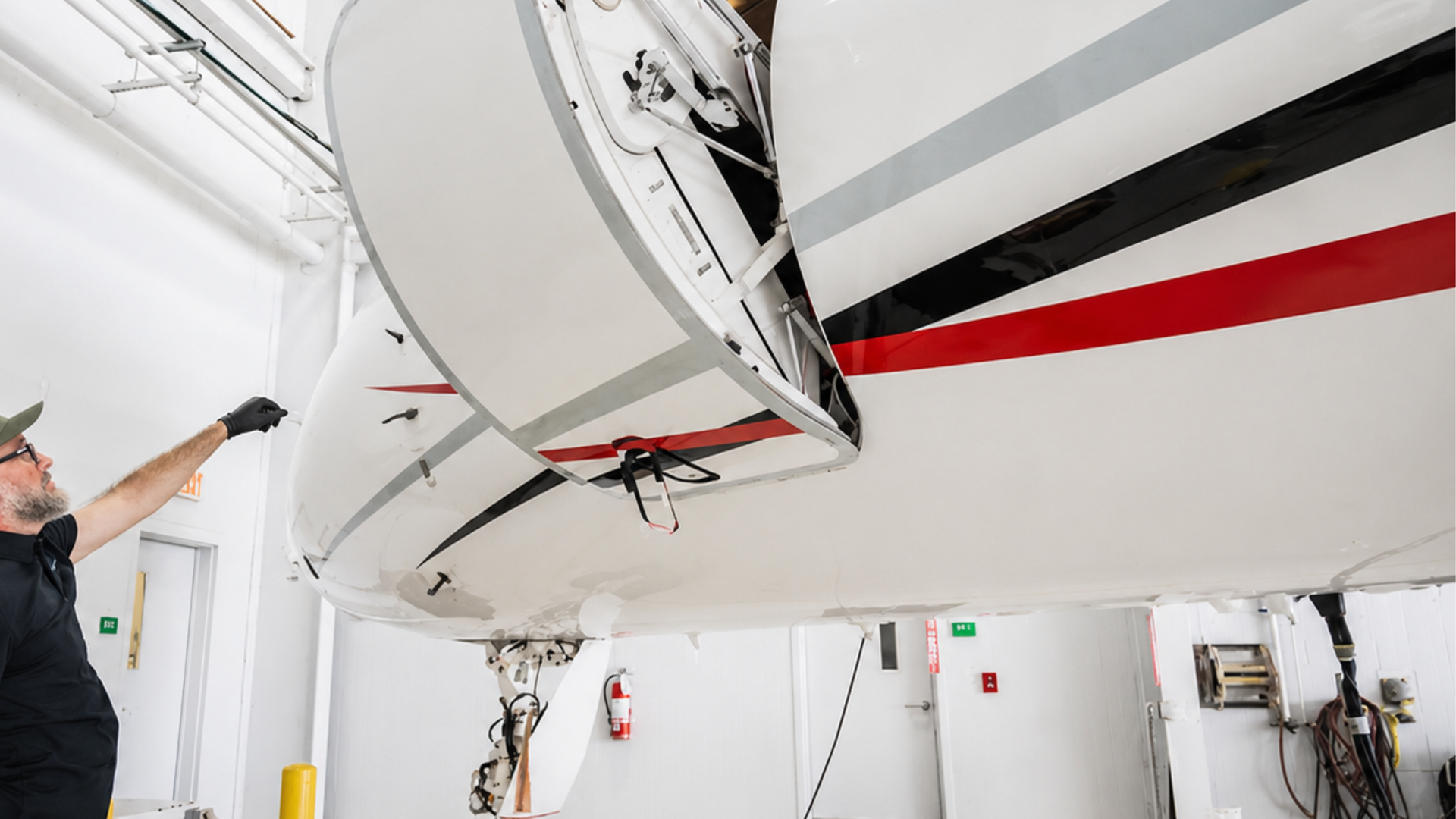 Technician inspecting the underside of a white aircraft in a bright hangar