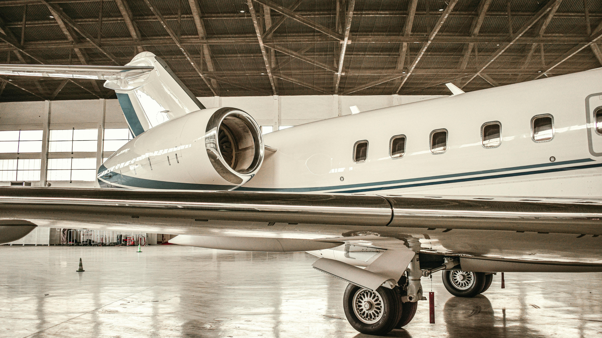 Private jet in a hangar, showing the rear fuselage, engine, and landing gear.