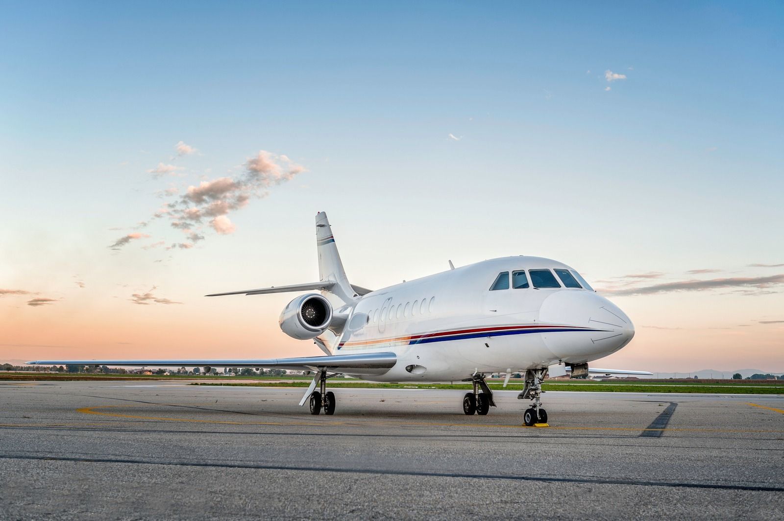 Private jet on a runway at sunset, with a clear sky and warm horizon.