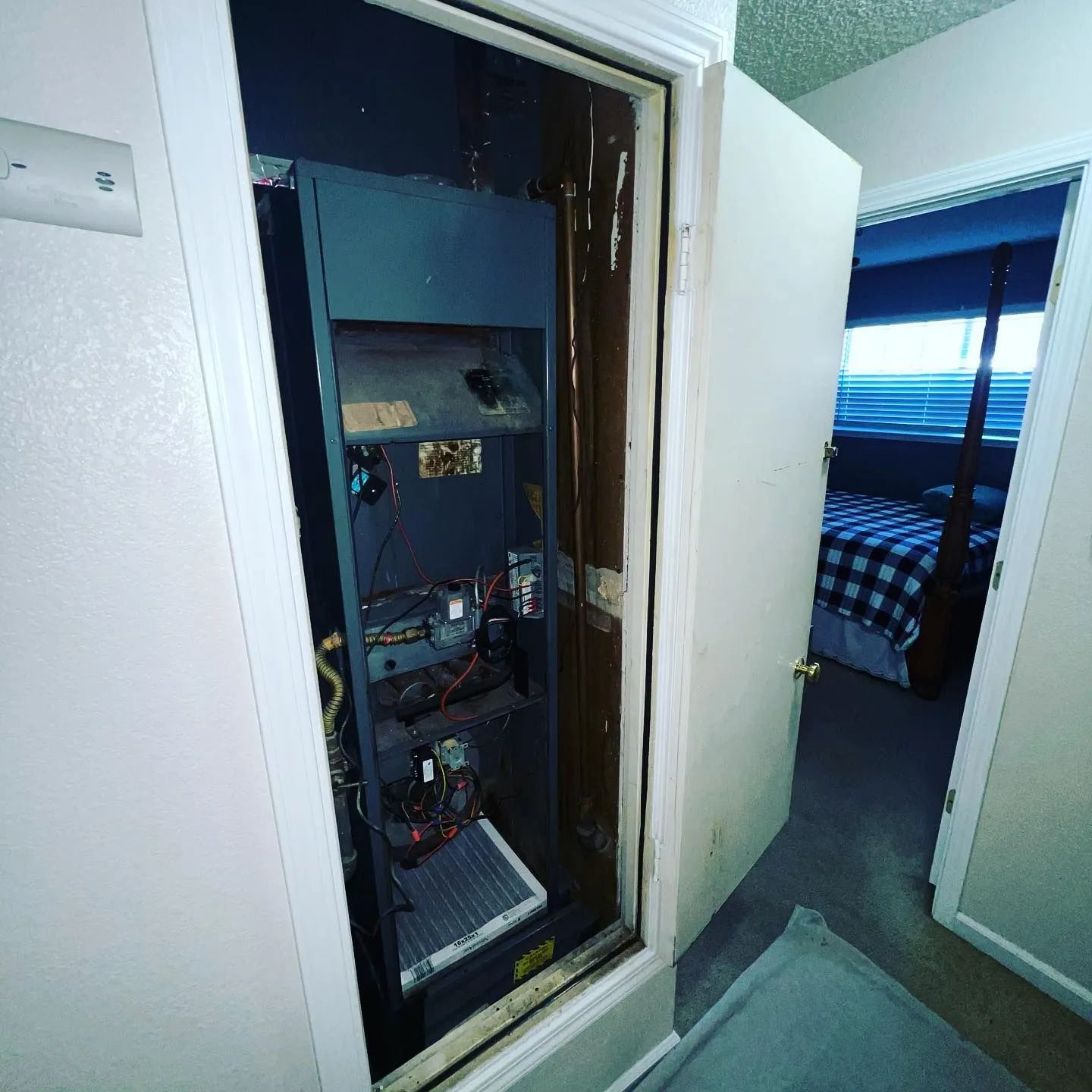 Open electrical panel in a hallway closet next to a bedroom doorway