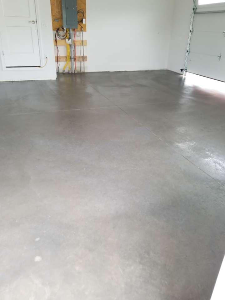 Empty garage with a polished concrete floor, white walls, and a partially open garage door.
