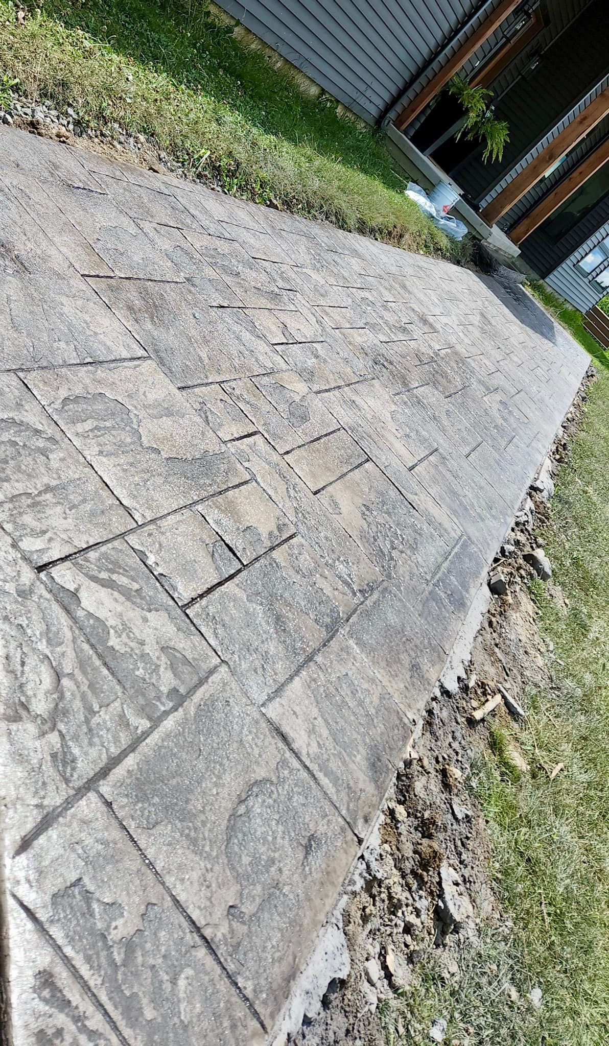 Brick walkway bordered by green grass and dirt.