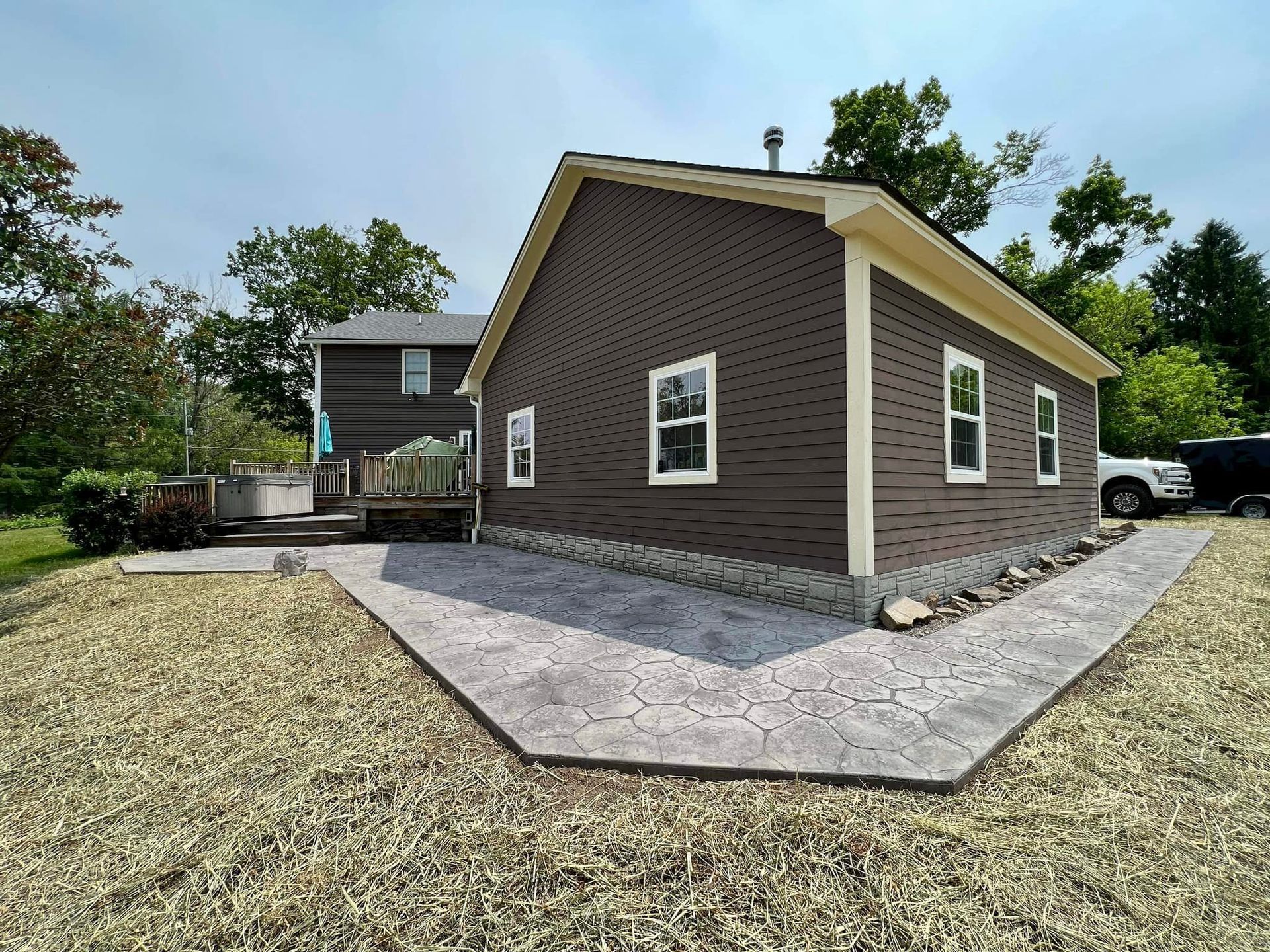 Brown sided building with concrete path on a grassy lawn.
