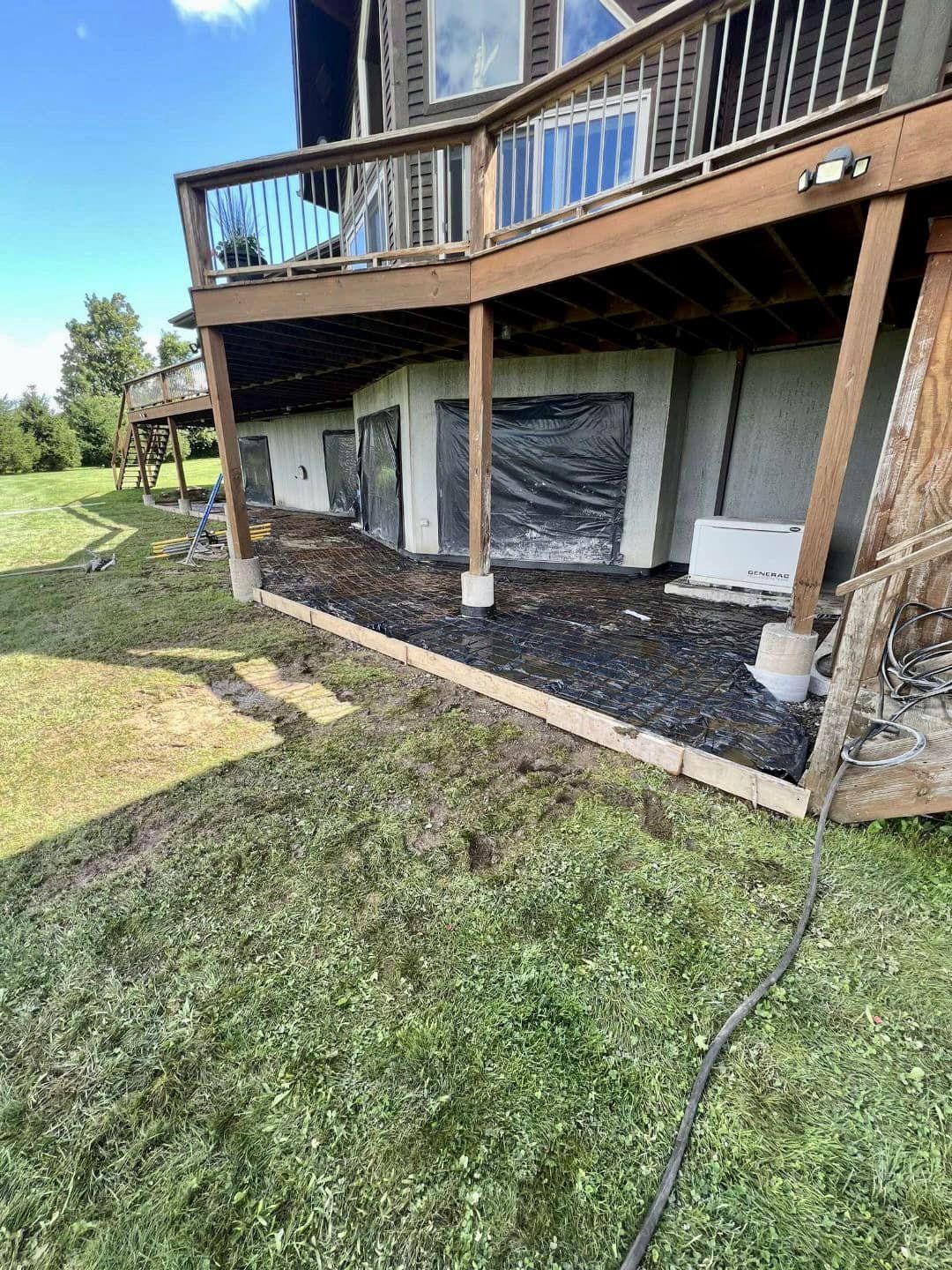 Wooden deck and house with a dark mulch border along the foundation. Green grass in the foreground.