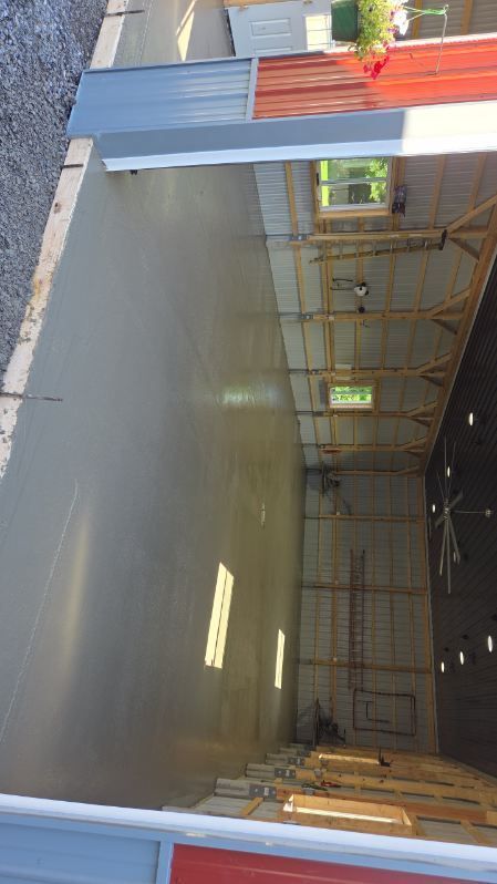 Empty warehouse interior with concrete floor, metal framing, and an orange overhead beam.