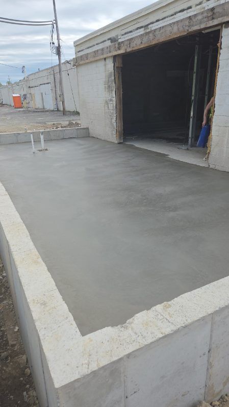 Concrete rooftop terrace beside an open garage doorway, with white parapet walls and a bench nearby