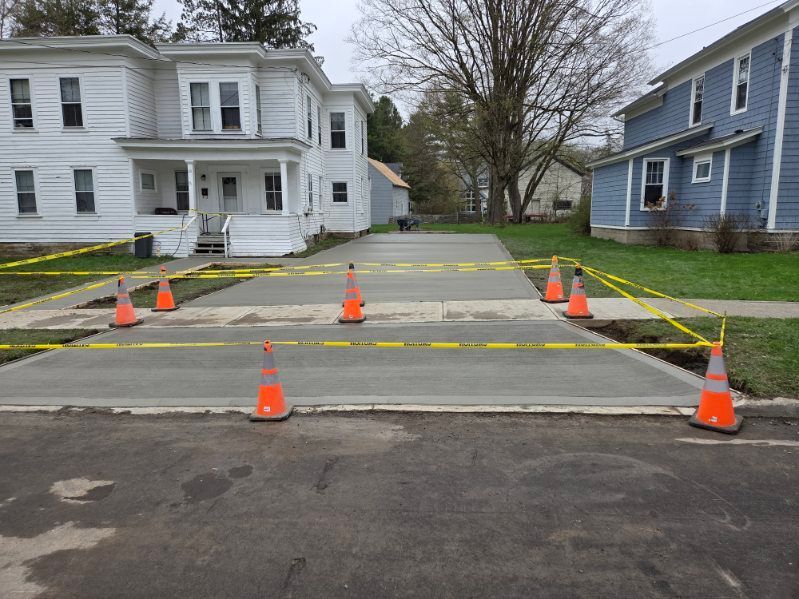 Blocked roadway with orange cones and caution tape in front of two houses