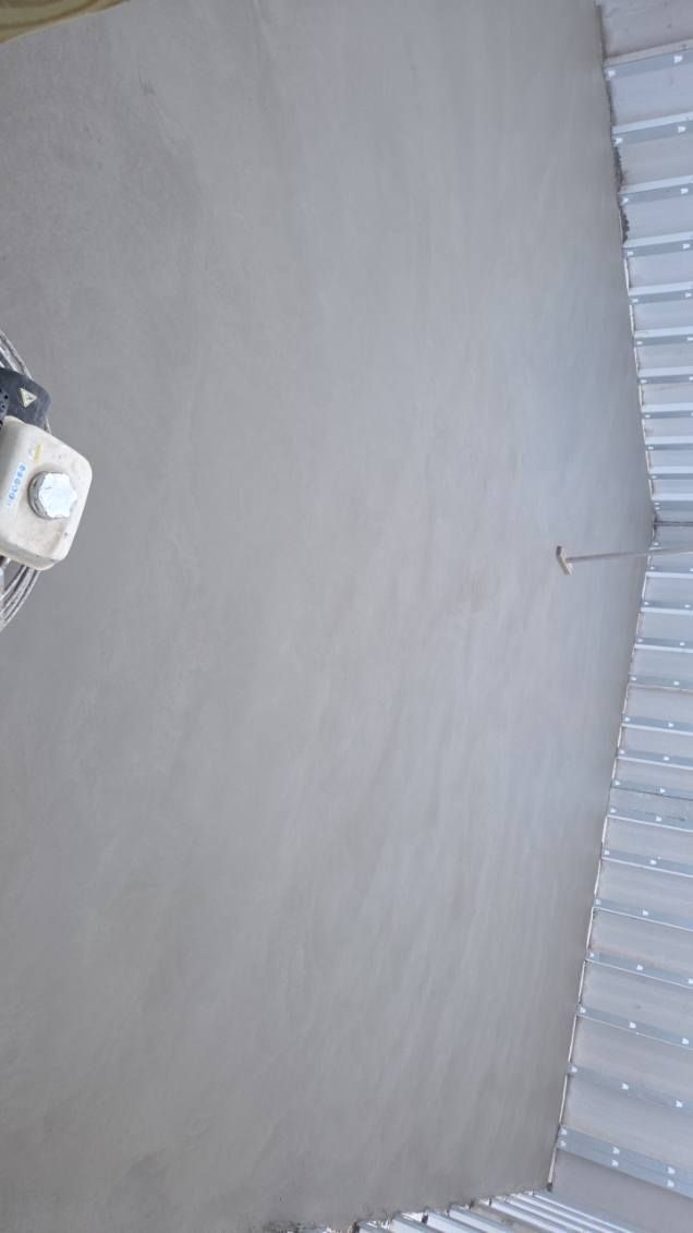Plain gray wall beside a white corrugated metal roof, with a small hanging hook.