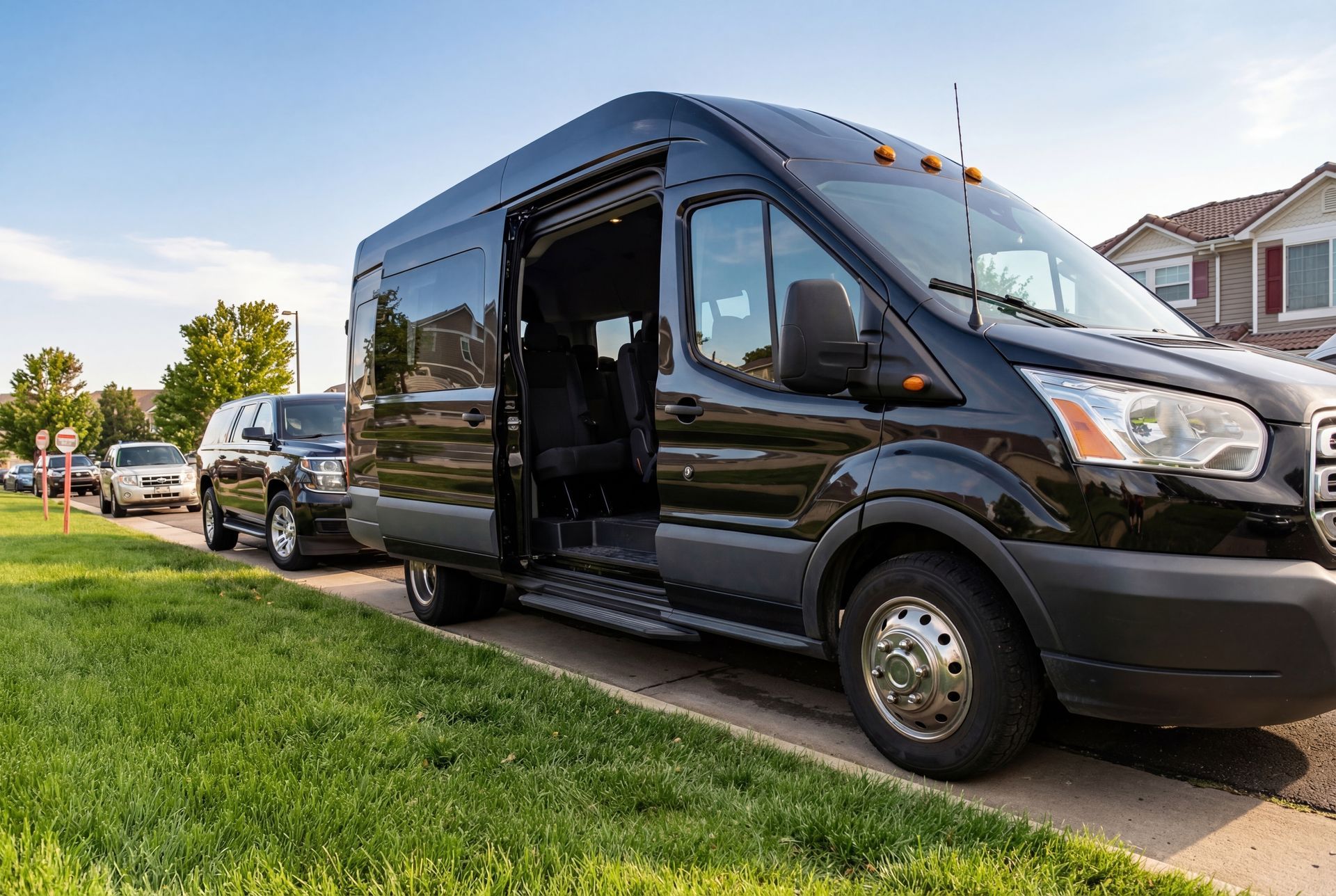 A black passenger van is parked on a residential street with its sliding door open.
