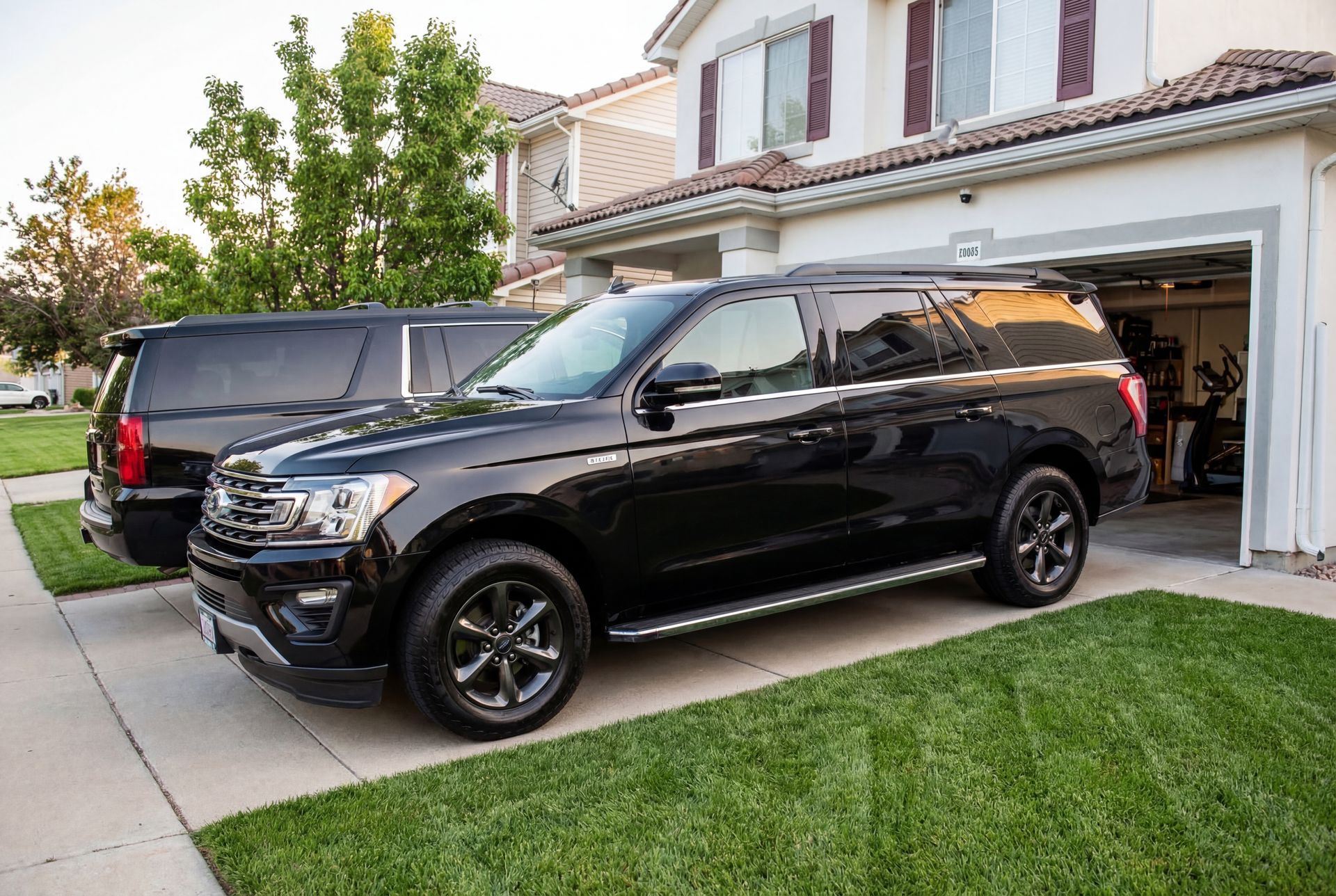 Black SUV parked on a driveway in front of a house, with another SUV visible behind it.