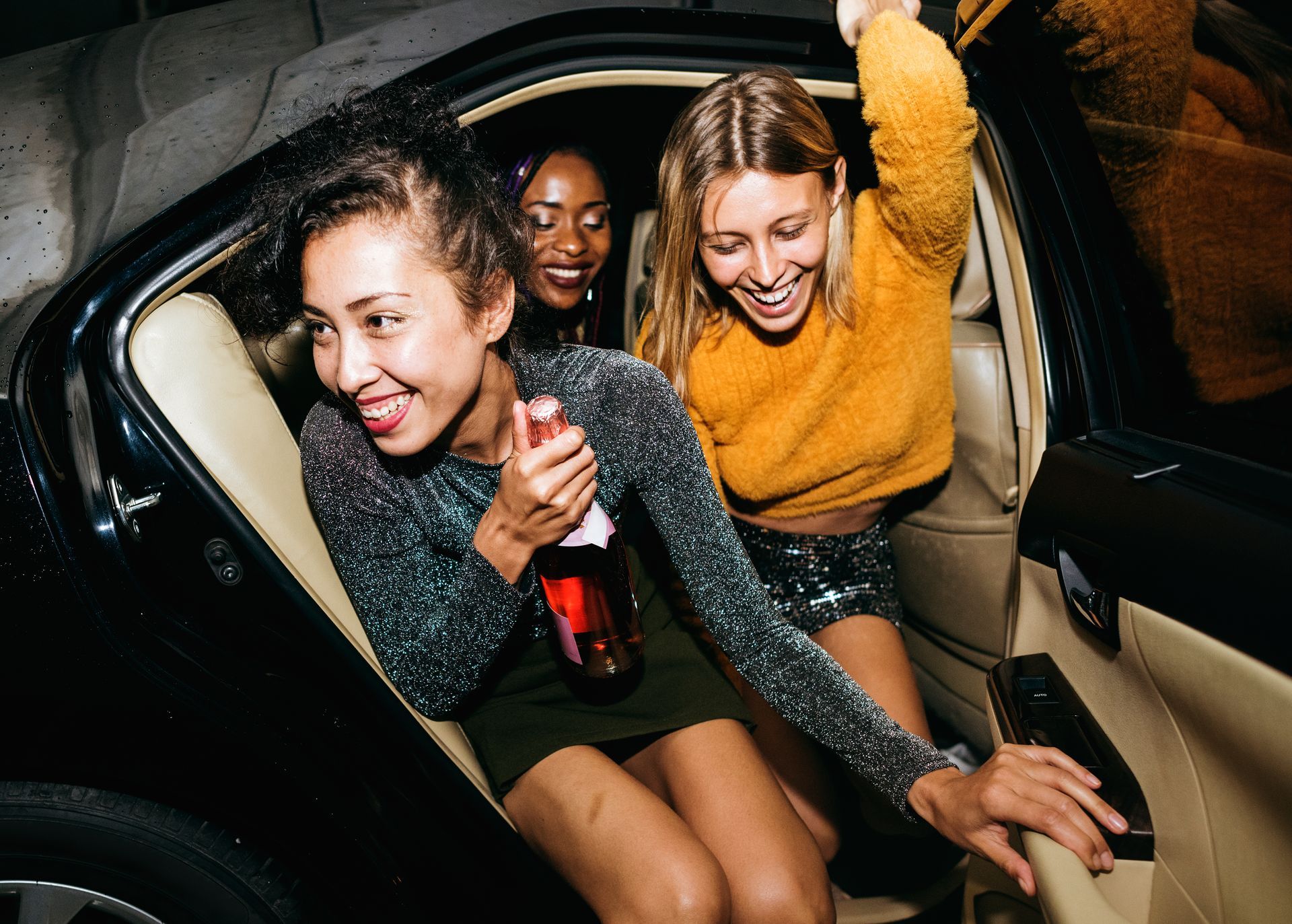 Three women are sitting in the back seat of a car.