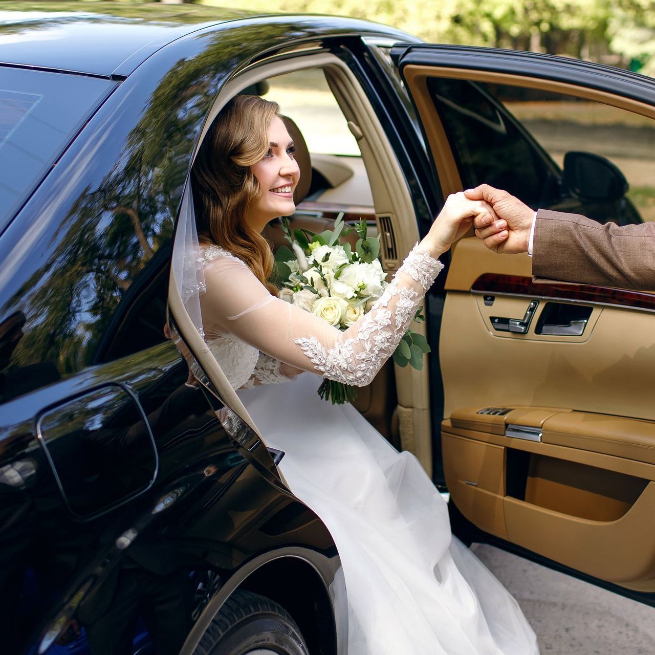 A bride and groom are shaking hands in a car