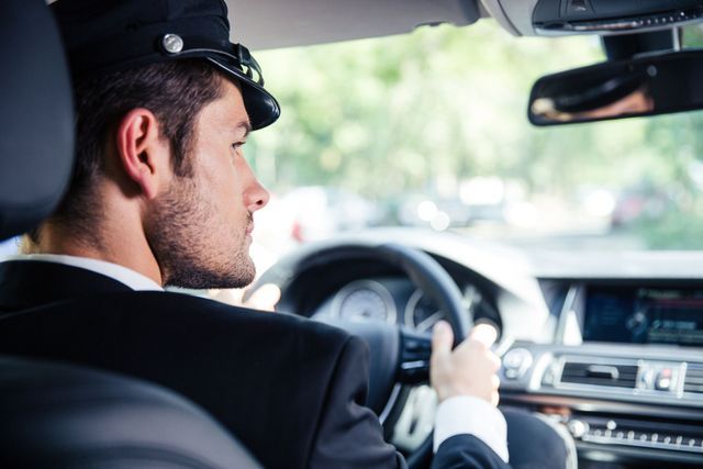 A man in a suit and hat is driving a car.