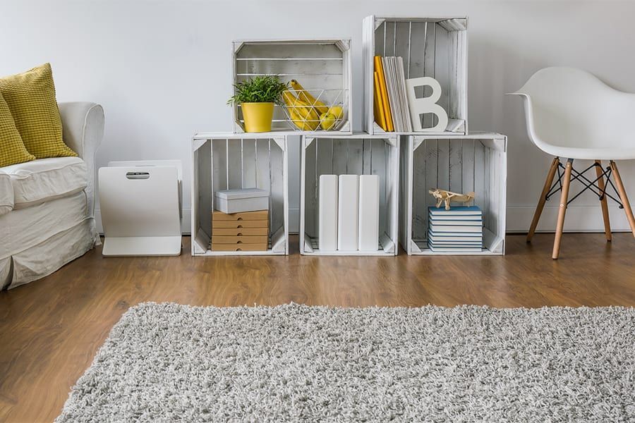 A living room with a rug , a couch , a chair and a shelf made of wooden crates.