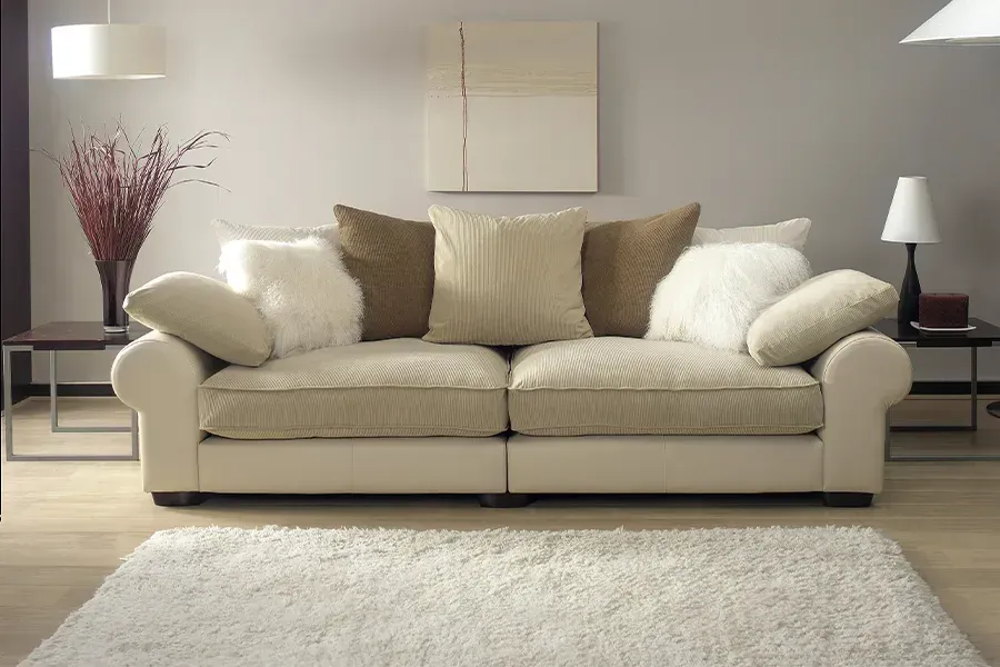 A living room with a white couch and brown pillows