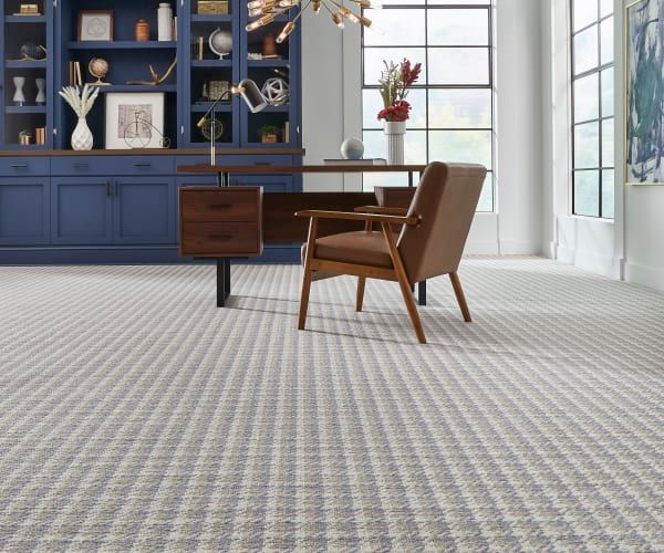 A home office with a desk and chair and a carpeted floor.