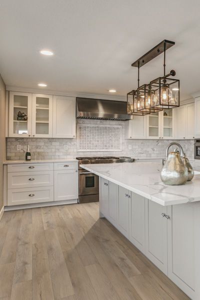 A kitchen with white cabinets , stainless steel appliances , and a large island.