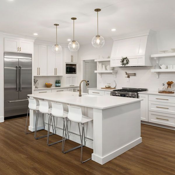 A kitchen with white cabinets , stainless steel appliances , and a large island.