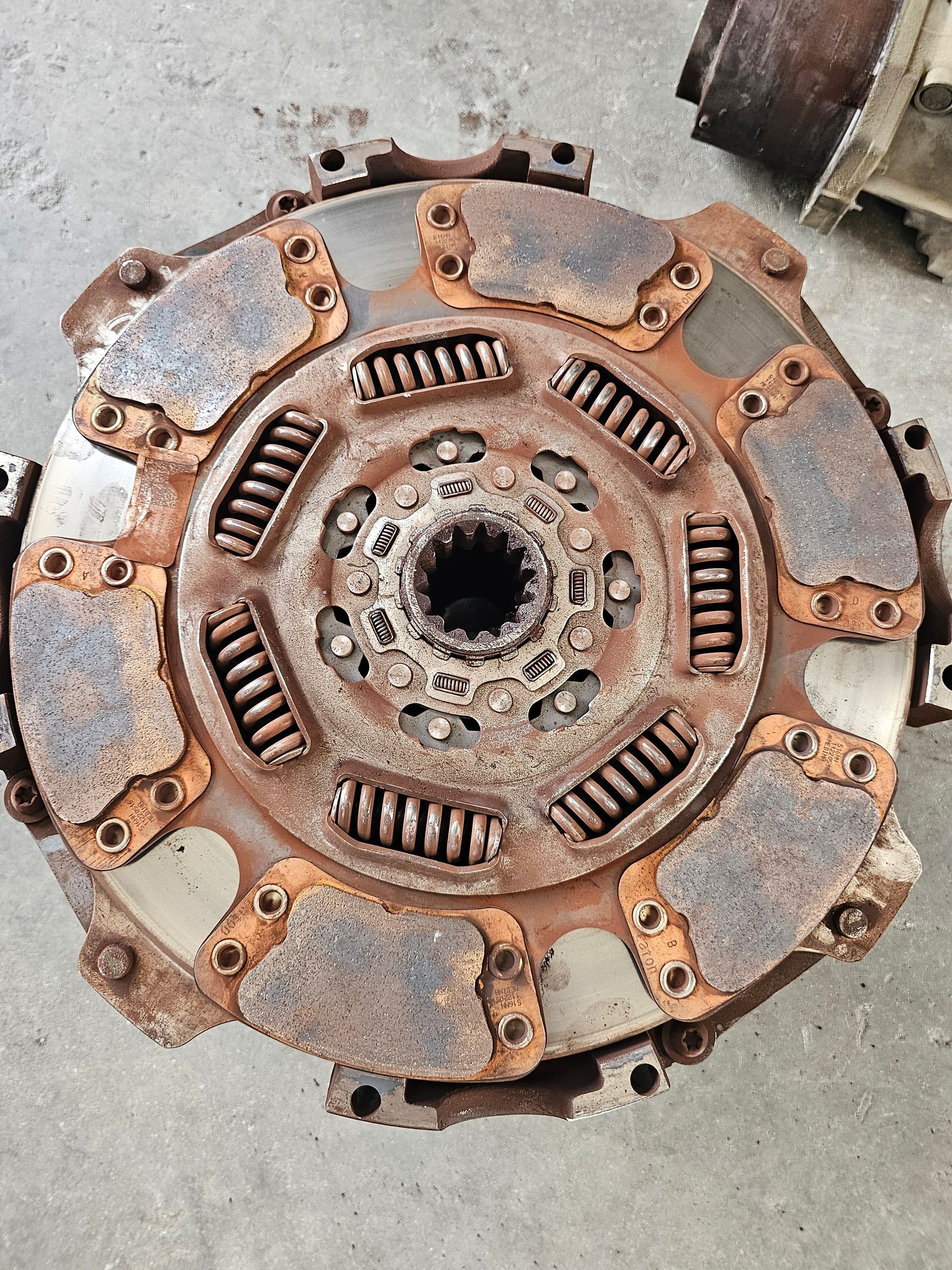 Rusty clutch disc with exposed springs and worn metal pads, viewed from above.