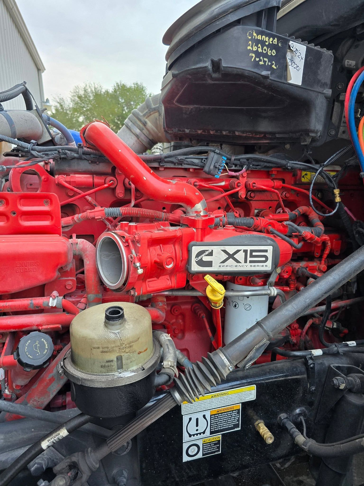 Close-up of a red truck engine with black hoses and a silver “6X9” badge in a garage.