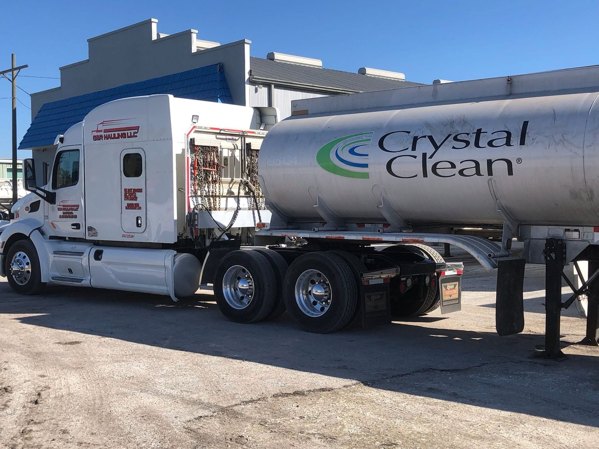 Crystal Clean tanker truck parked beside an industrial building on a sunny day