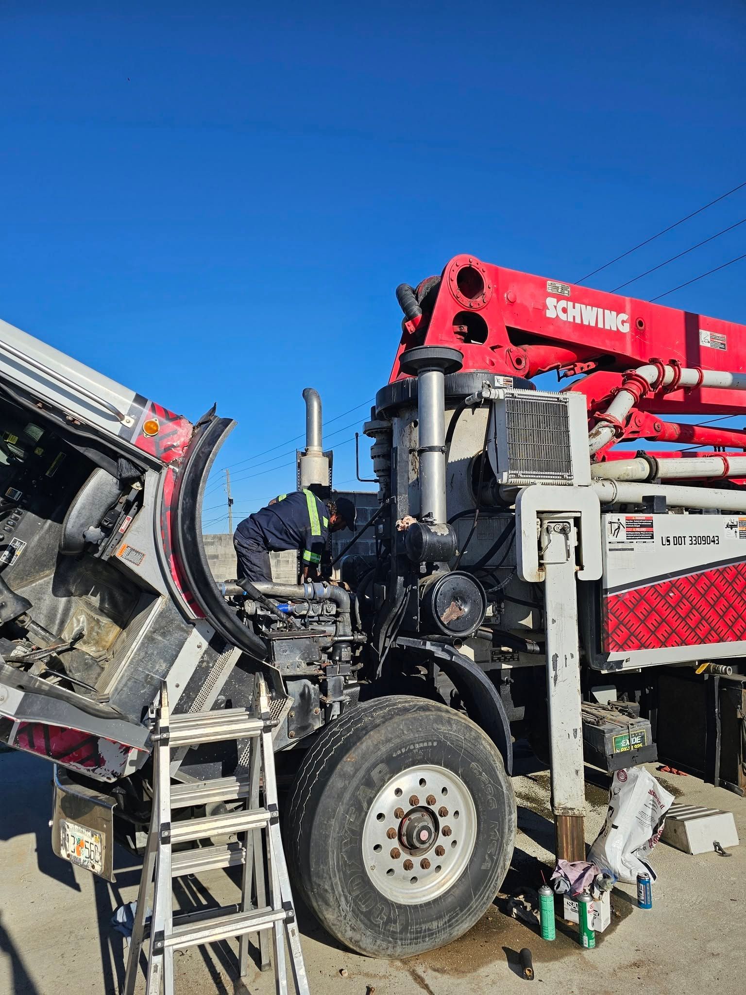 Red construction machinery with a large wheel and crane arm against a blue sky