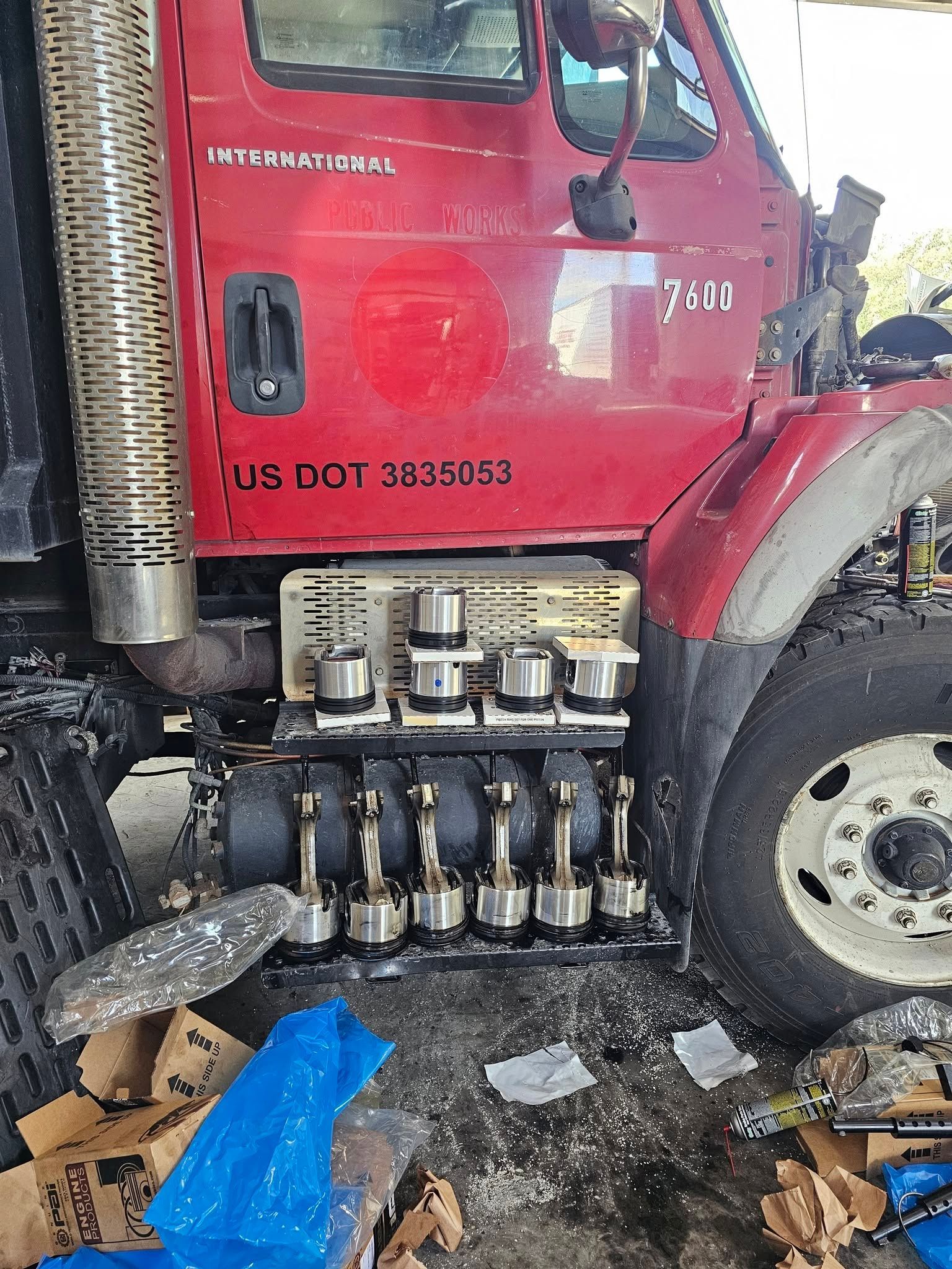 Red truck cab with damaged side panels and exposed fuel tanks, debris scattered on the ground.