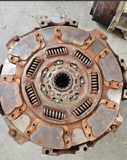 Rusty worn clutch disc with springs, shown close-up on a workshop floor