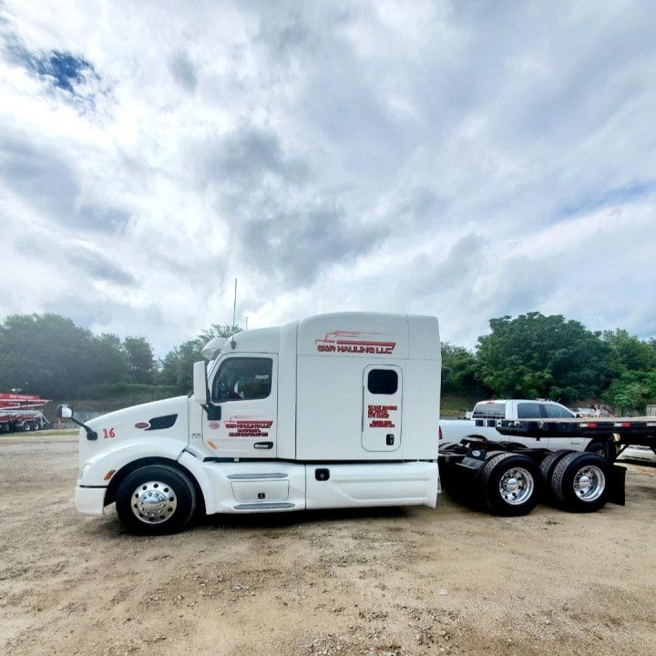 White semi-truck tractor parked on a gravel lot under a cloudy sky