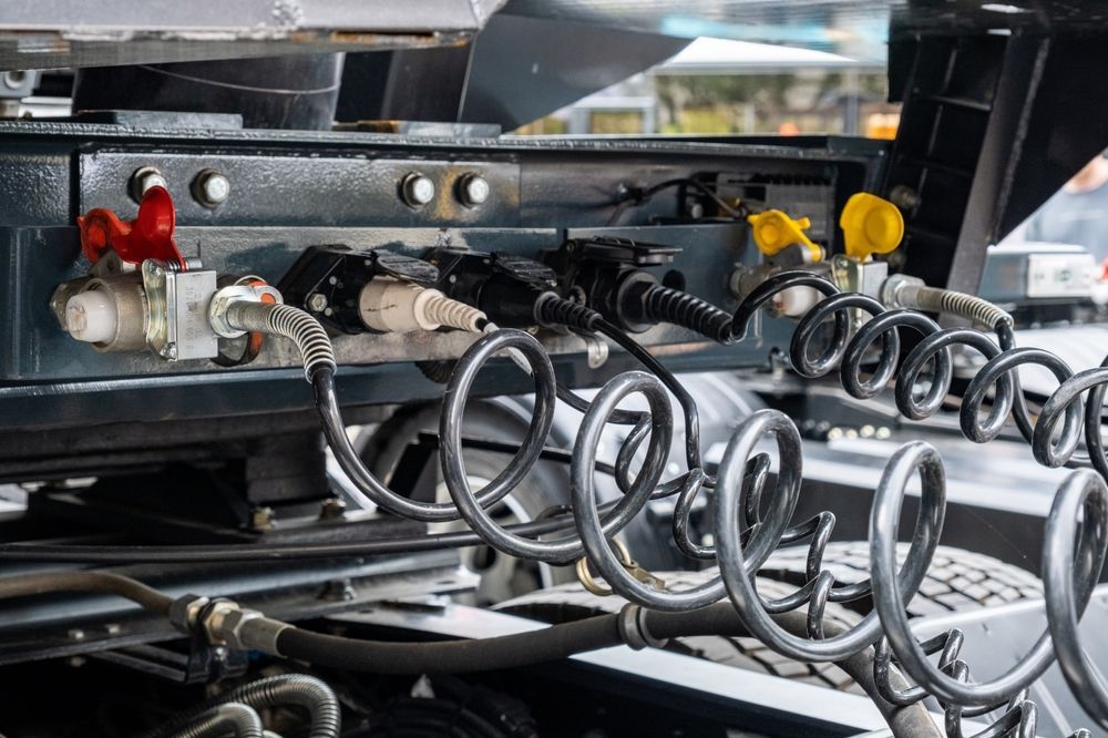 Coiled metal hoses and colored fittings on industrial machinery in a factory setting