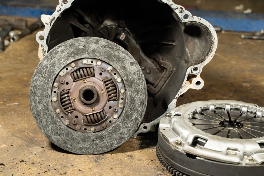 Two clutch assemblies on a workbench, one mounted on a transmission housing and one lying beside it