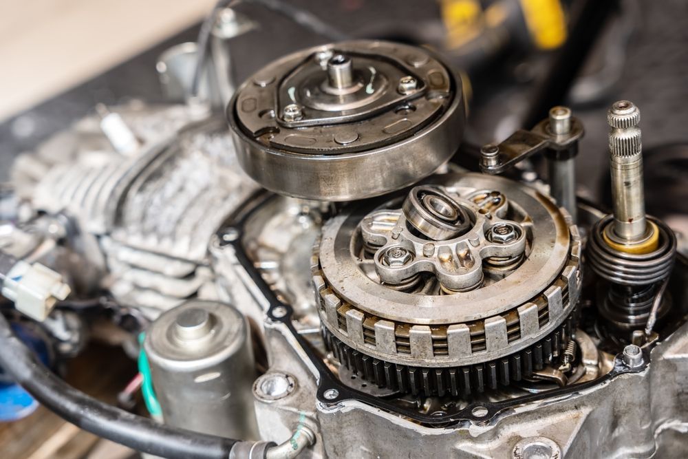 Close-up of an exposed mechanical engine with gears, pulleys, and metal components.