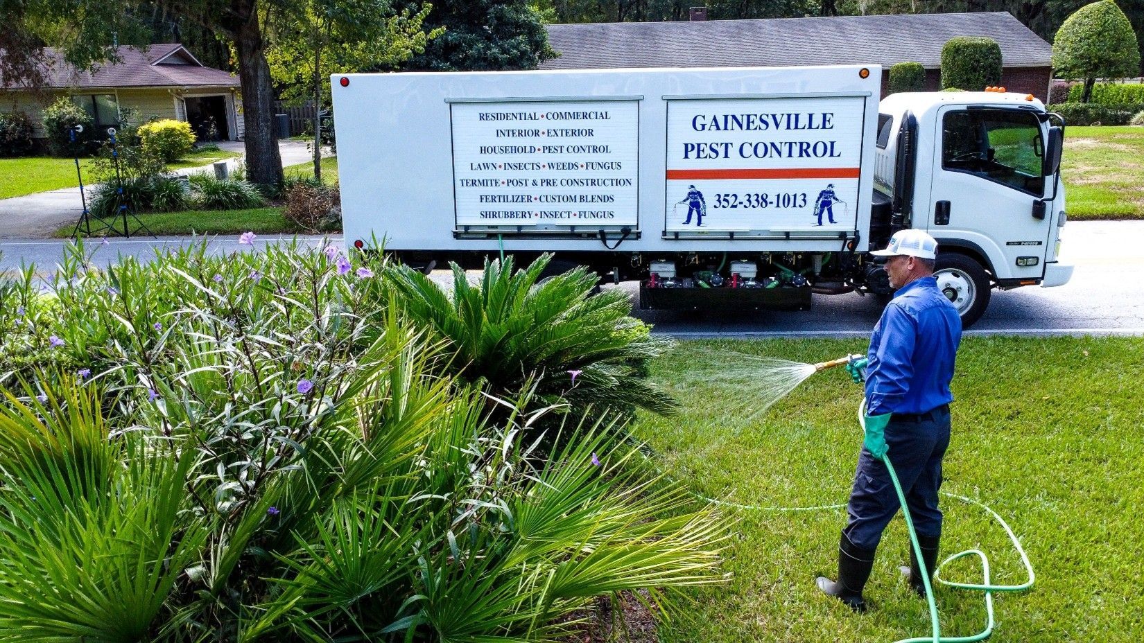 Man sprays lawn with hose, pest control truck in the background. Man sprays lawn with hose, pest control truck in the background.
