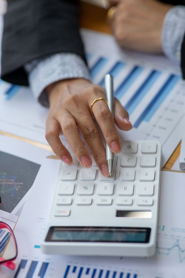 A woman is using a calculator and a pen while sitting at a table.