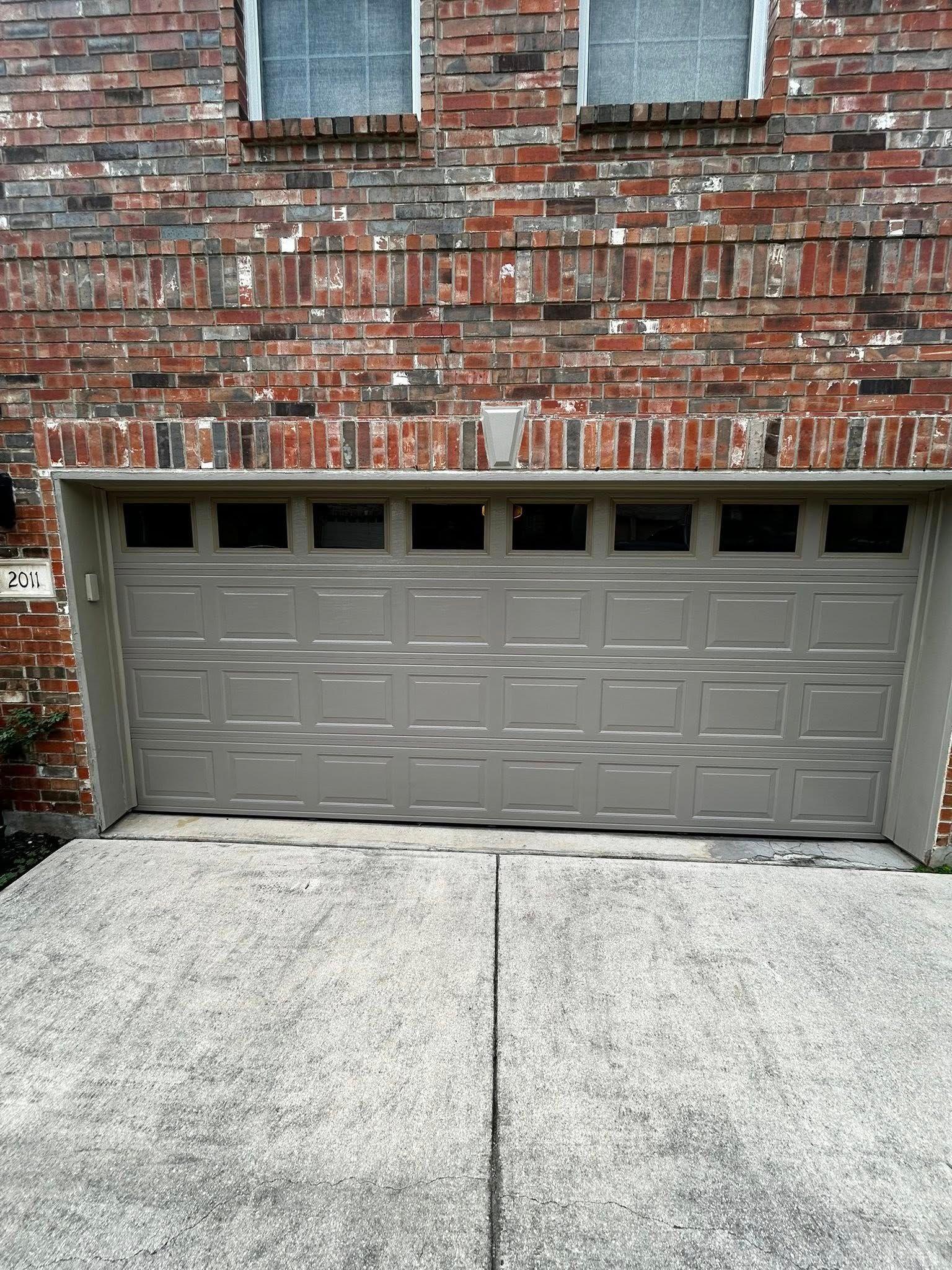 Brick house exterior with gray garage door and concrete driveway