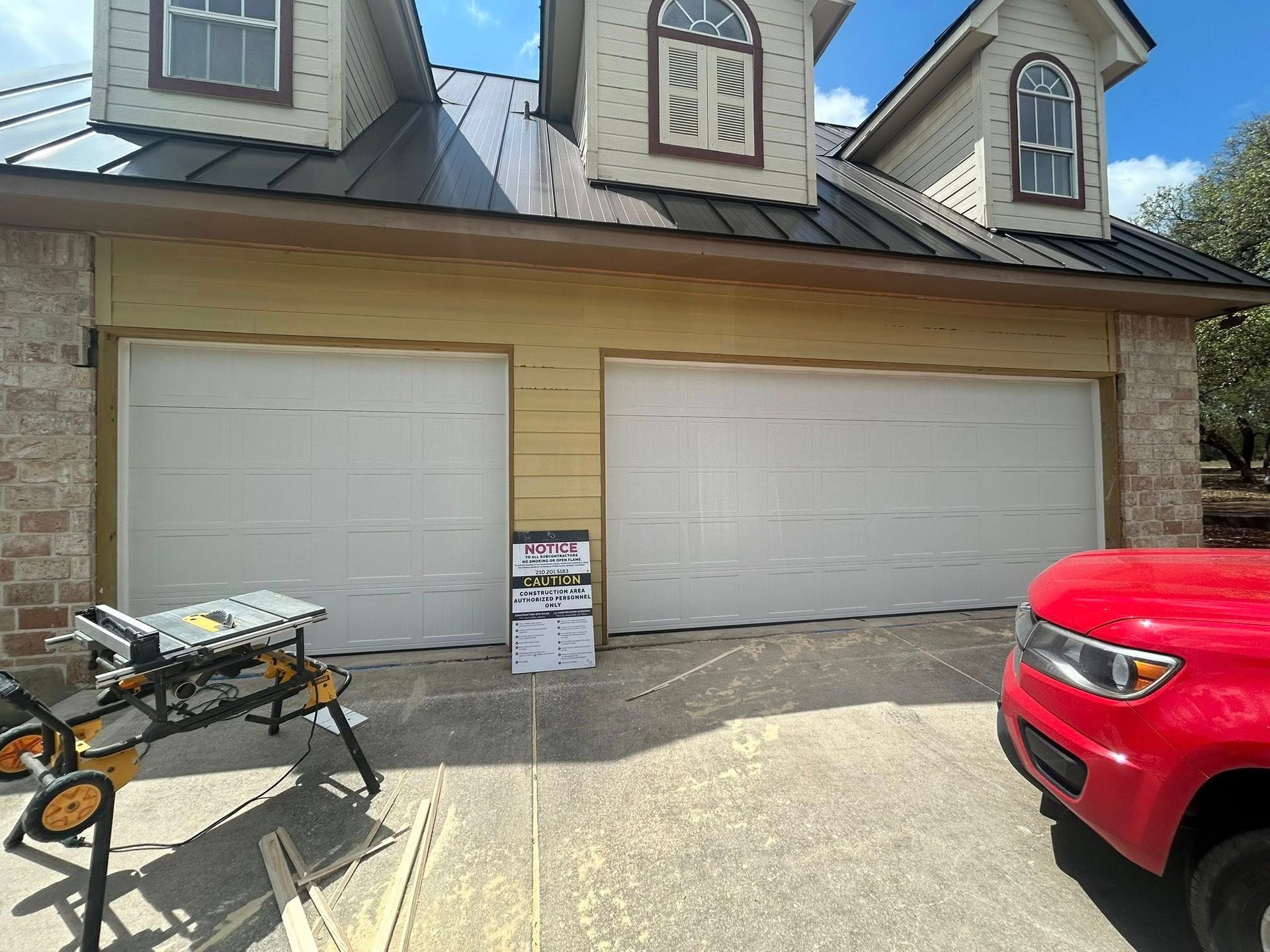 Two-car garage with white doors, driveway, red SUV, and a folded utility cart in front.