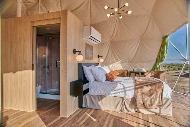 Modern bedroom with gray accent wall, green bedding, wall lights, and air conditioner above the bed