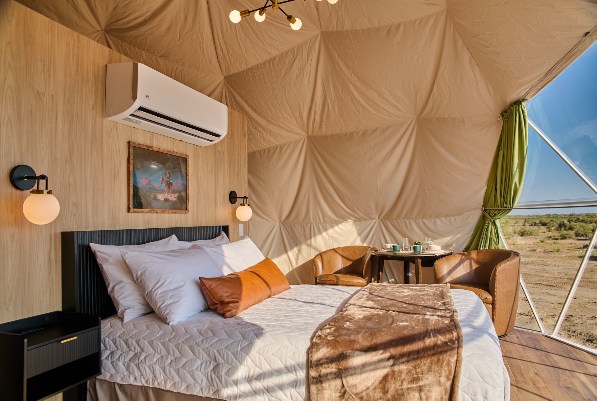 Luxury safari tent bedroom with a bed, wood paneling, and desert view outside