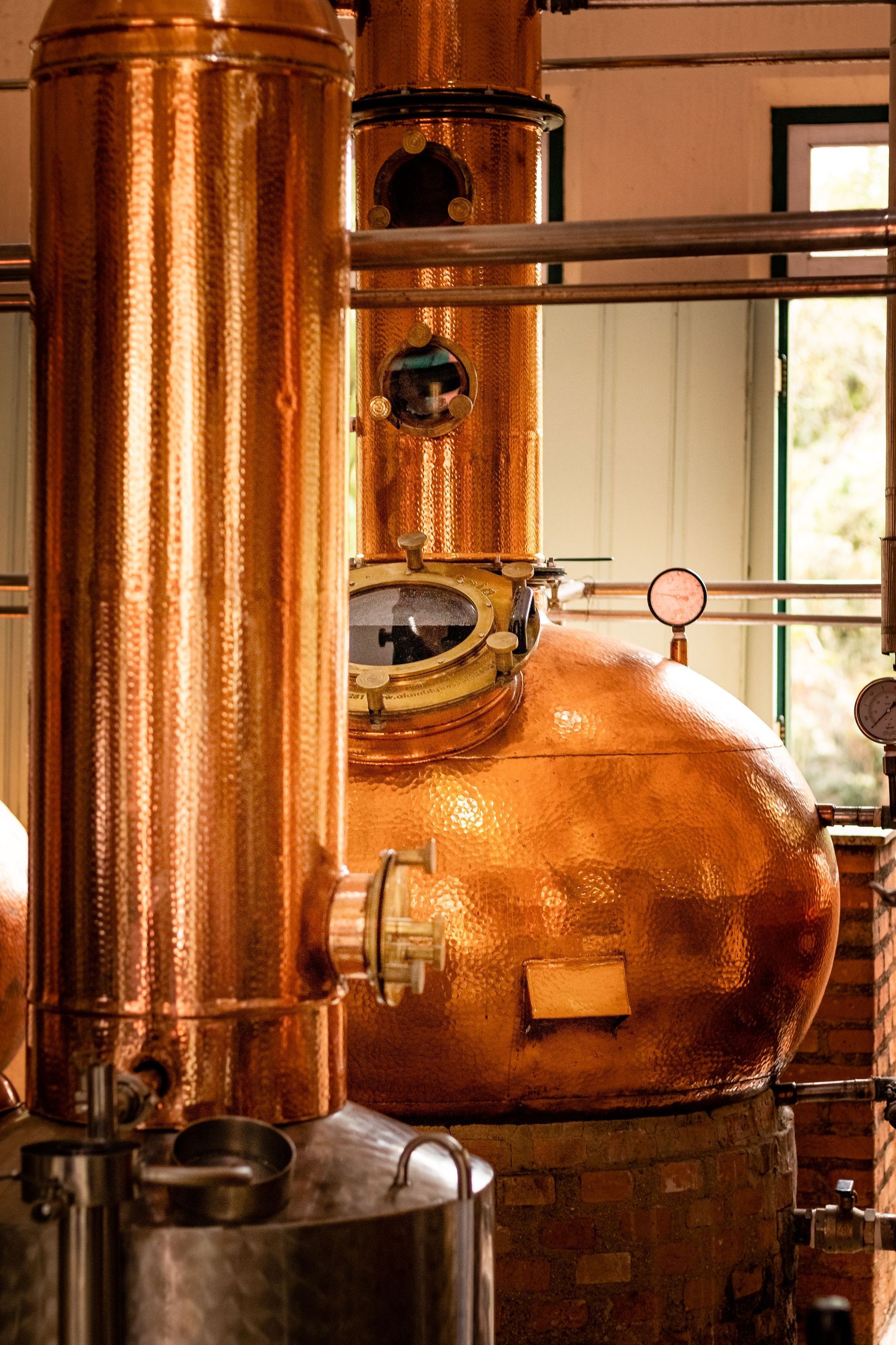 Copper distilling equipment with pipes and a round boiler in an industrial interior