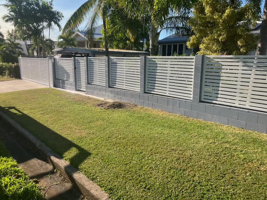 Grey and White Horizontal Slat Fence With Grey Brick Base in Front Yard, Green Grass and Trees — Gate-O-Matic in Garbutt, QLD