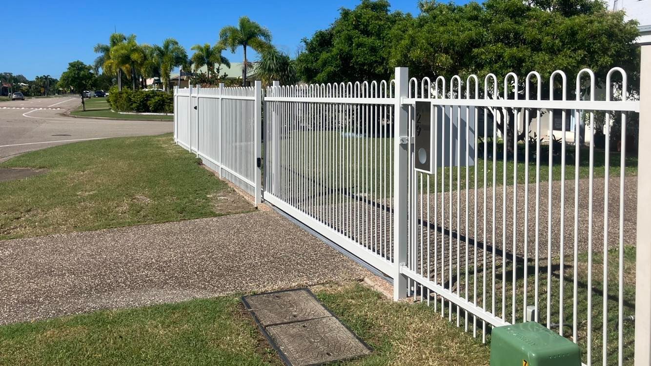White Metal Fence Along a Grassy Area, a Driveway, and Trees. Sunny Day — Gate-O-Matic in Garbutt, QLD