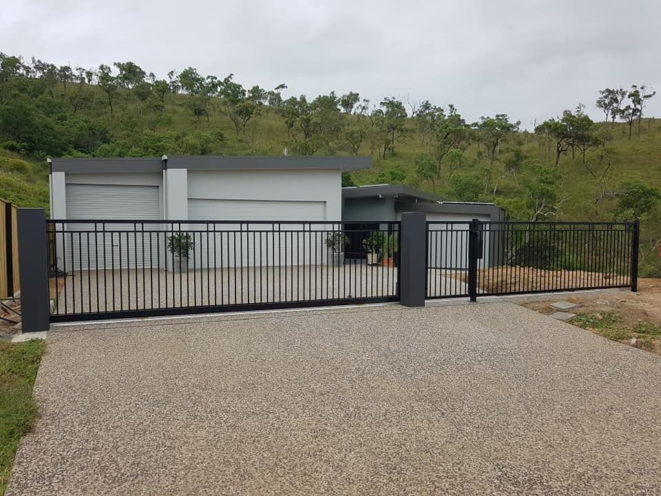 Black Metal Gate in Front of a Modern House With a Gravel Driveway Against a Hillside — Gate-O-Matic in Garbutt, QLD