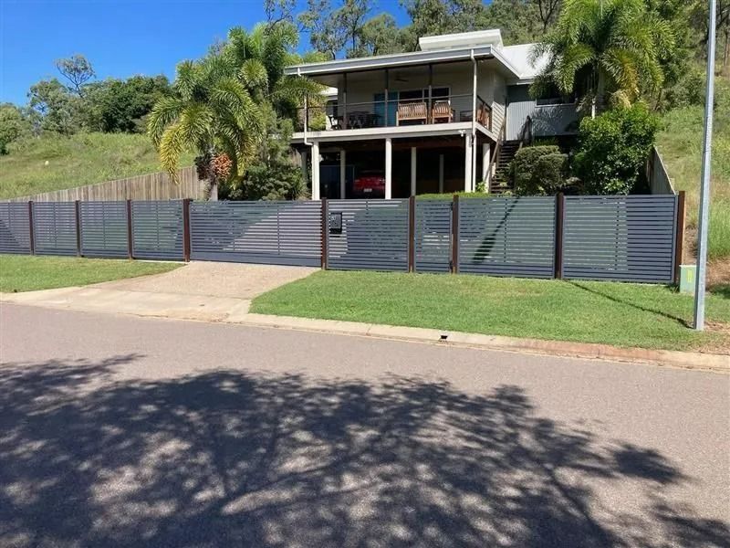 House With Grey Fence and Driveway. Green Grass in Front, Trees in the Background, Blue Sky — Gate-O-Matic in Garbutt, QLD
